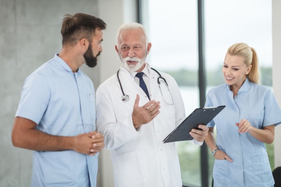 A small team of health care staff talking together in a bright corridor