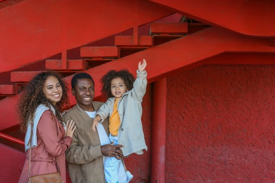 Three people standing together against a bright red wall
