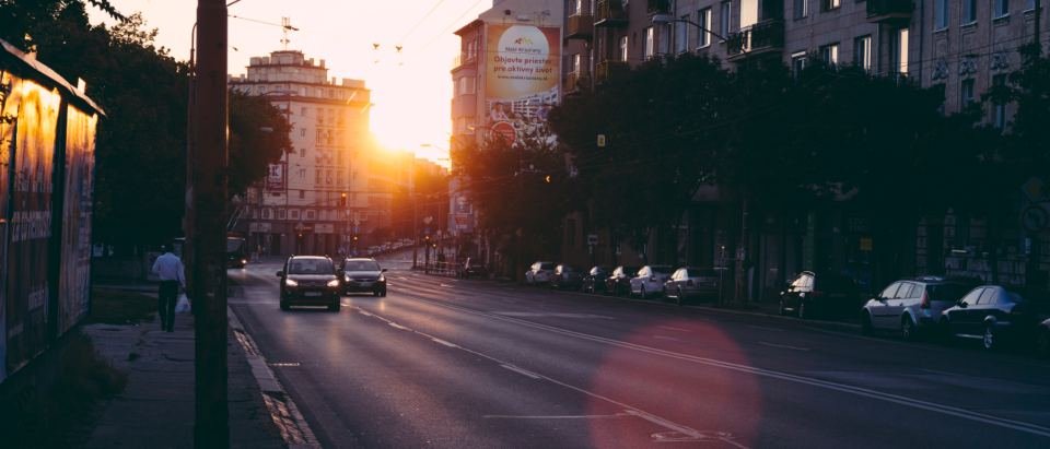 An empty city street at sunrise with the sun low between buildings
