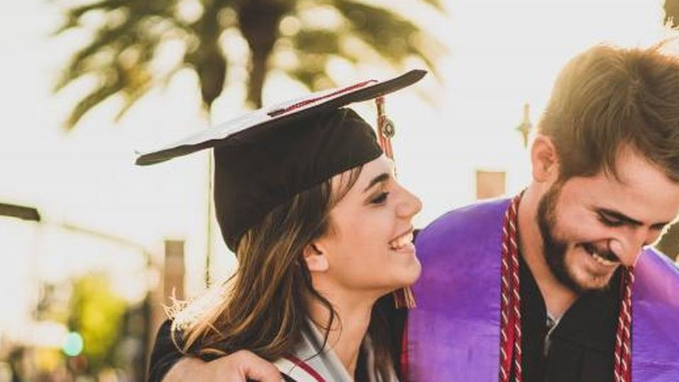 Two graduates embracing outdoors in warm afternoon light