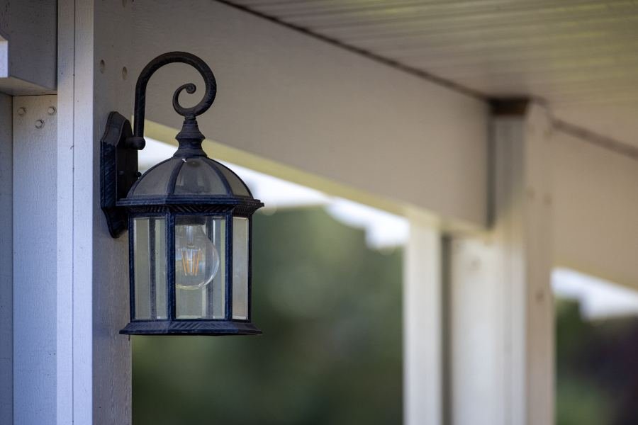 A lantern light beside a house porch at dusk