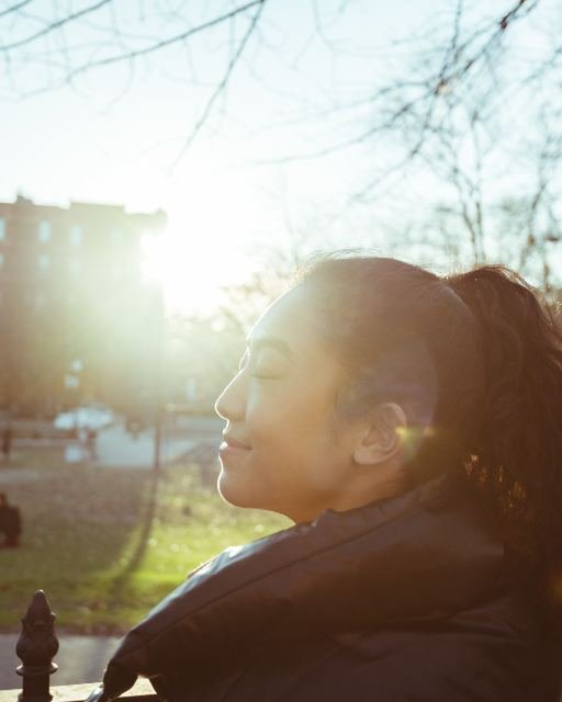 A woman photographed in profile against warm afternoon sunlight