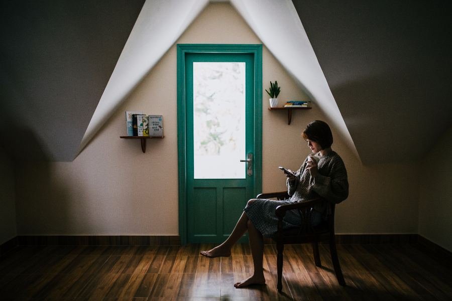 A person sitting alone in a quiet room beside a green door