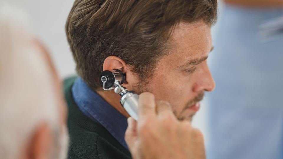 A close view of a practitioner examining a patient's ear with an otoscope