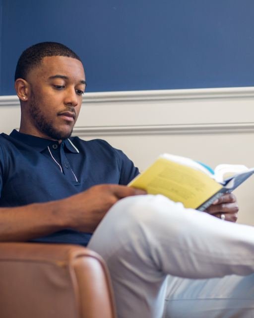 A man reading a book in an armchair at home