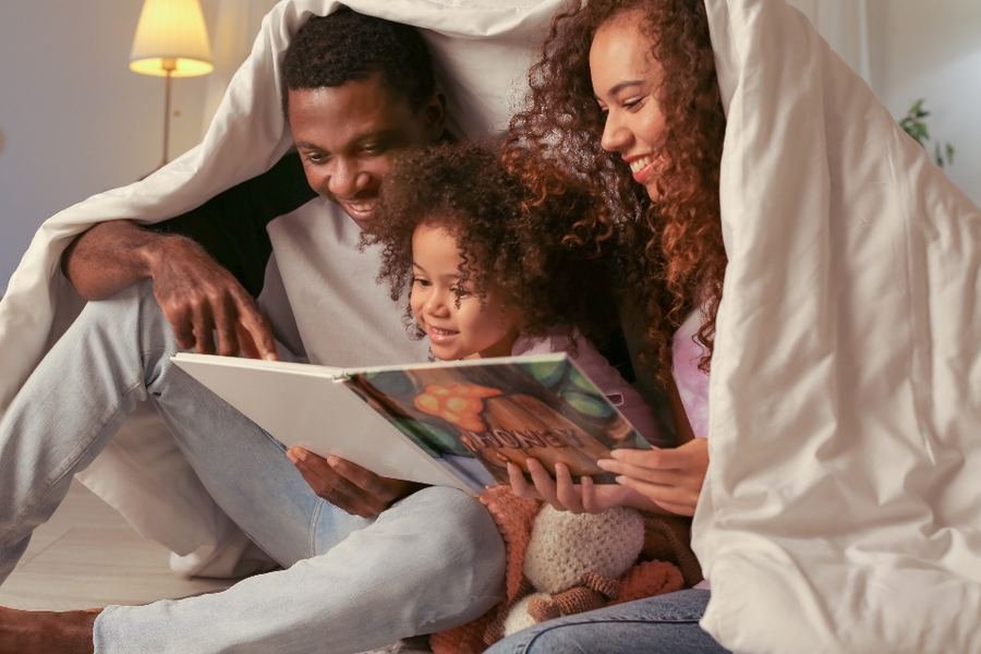 A family reading together under a blanket in soft daylight